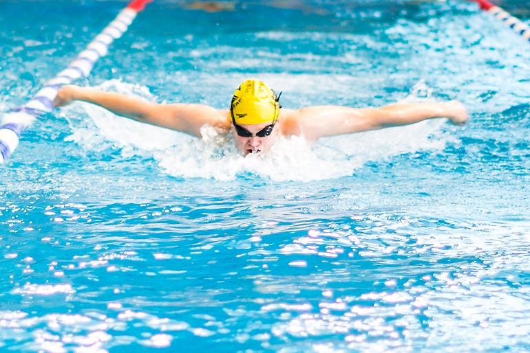 Ung simmare i full färd med att simma fjäril.